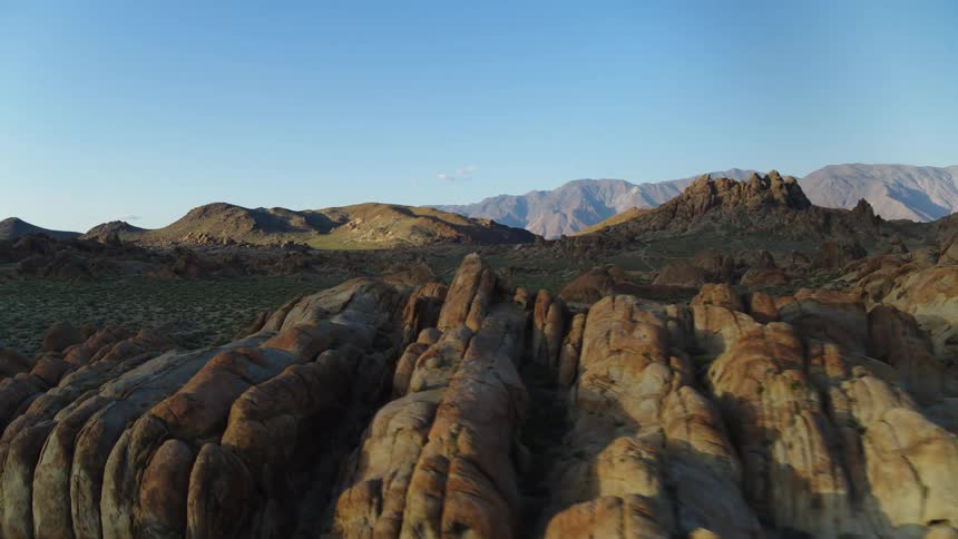 An aerial view of a grassy desert plain surrounded by rocky formations