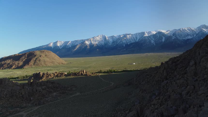 The long field leads to a mountain range