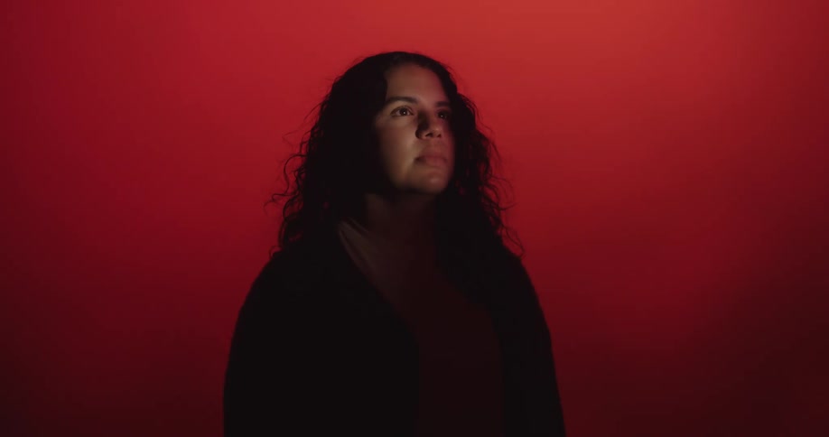 Woman silhouetted against red background turns to face light