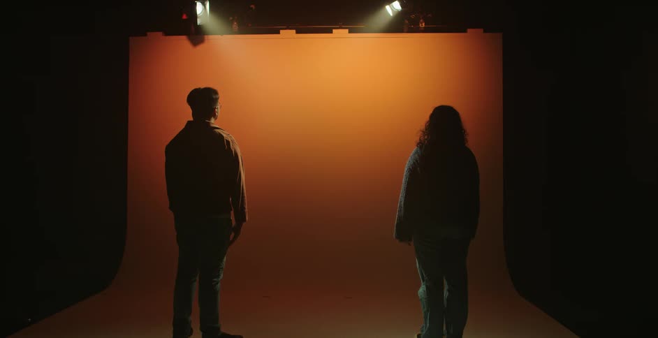 Two people are standing under the stage lights