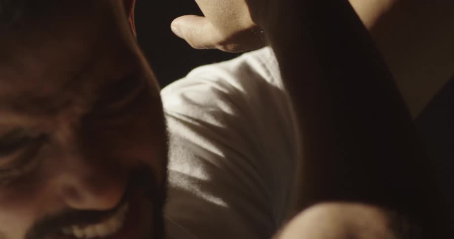 Flashing light illuminates grimacing man shielding his face with his arms