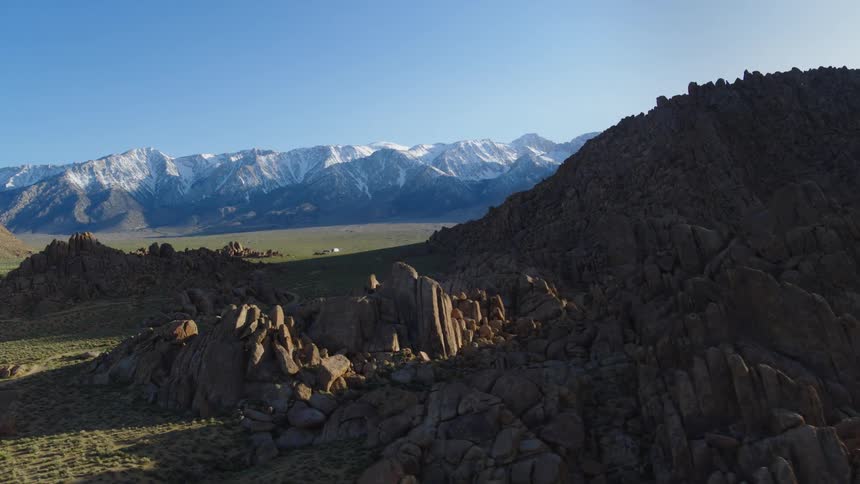 An aerial of a snow covered mountain range with a rocky mountain range along the range