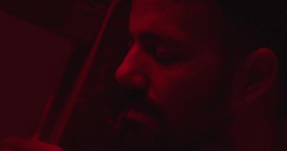 Close up of the face of a man inside a room dimly lit under red lights