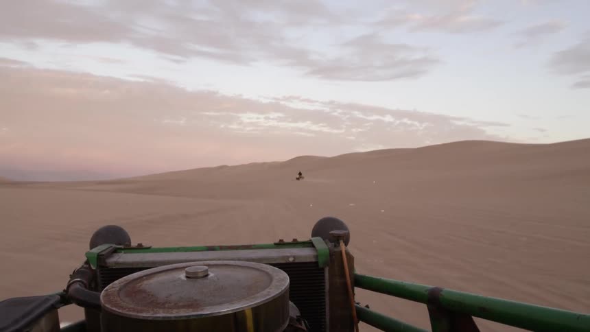 A vehicle is riding along a desert