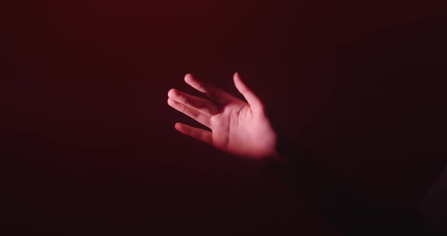 Just a hand moving in slow motion gracefully against a blackmagenta background with magenta light