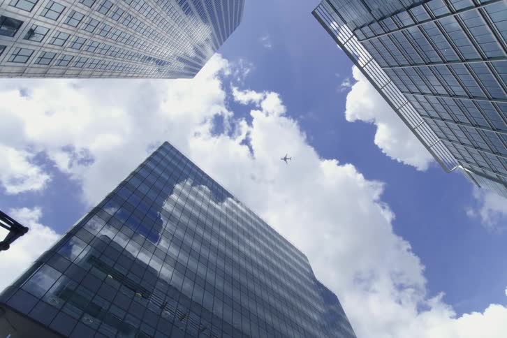 The plane flies over the tall buildings