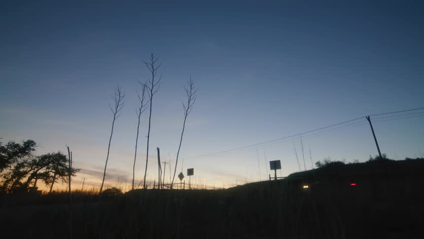 Automobiles travel on a country road as the sun is setting