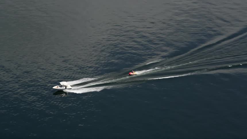 A speedboat tows a raft across Lake Washington leaving a double wake behind