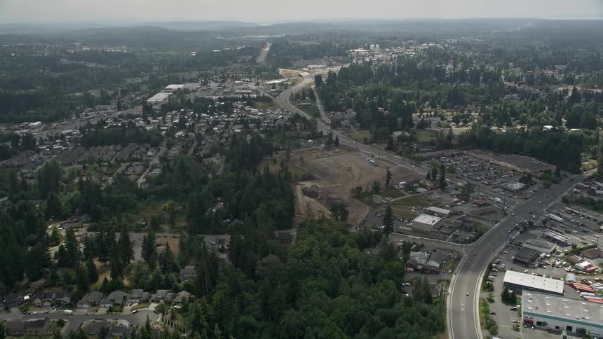 Aerial view flying over a suburban neighborhood passing between homes and warehouses before approaching a mobile home park in Lynnwood Washington