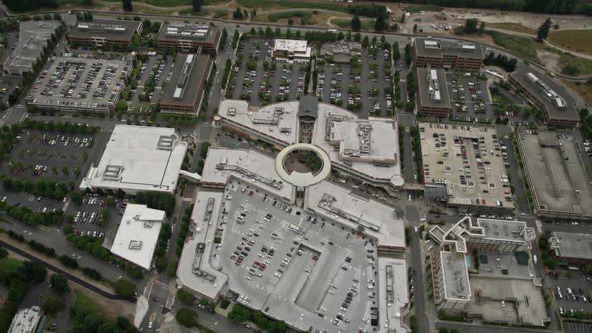 A birds eye view of Redmond Town Center shopping mall in Washington on a cloudy day tilting down from the sky to show the retail center and surrounding area