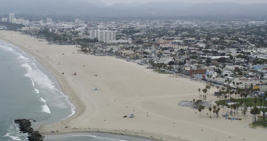 An aerial of the ocean meeting the sandy beach along a metropolitan area across the landscape