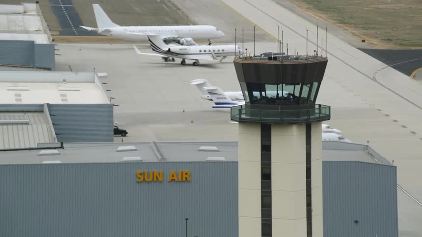 Airplanes sit on tarmac on opposite side of airline terminal from air traffic control tower