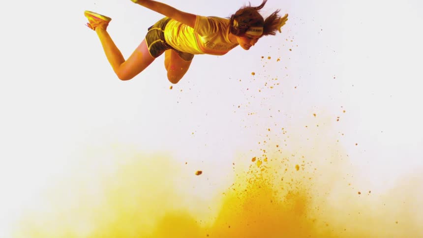 A young woman falls through the air above billowing yellow powder