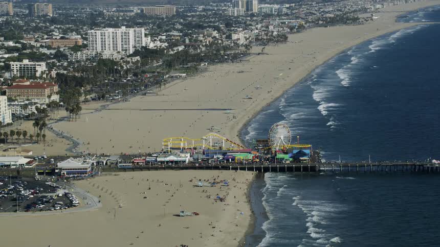 A large crowd hangs out on a beach and boardwalk