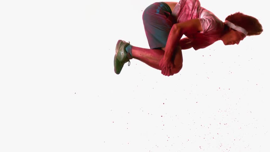 A man is doing a backflip covered in red powder