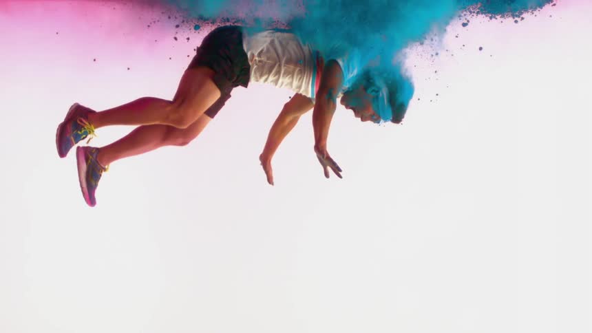 A young man falls through blue colored powder