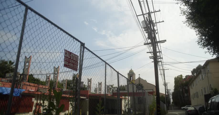 An alleyway with electric wires poles and a fence