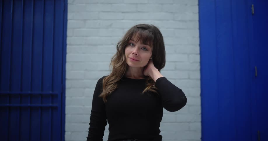Woman with brown bangs and black sweatshirt smiles at camera