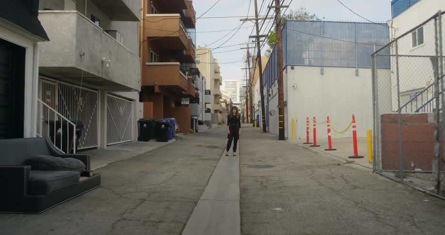 Young woman stands on the middle of an alleyway in town a daytime