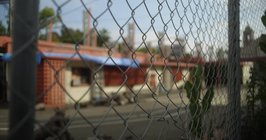 Close up of a chain linked fence separating a road and a house