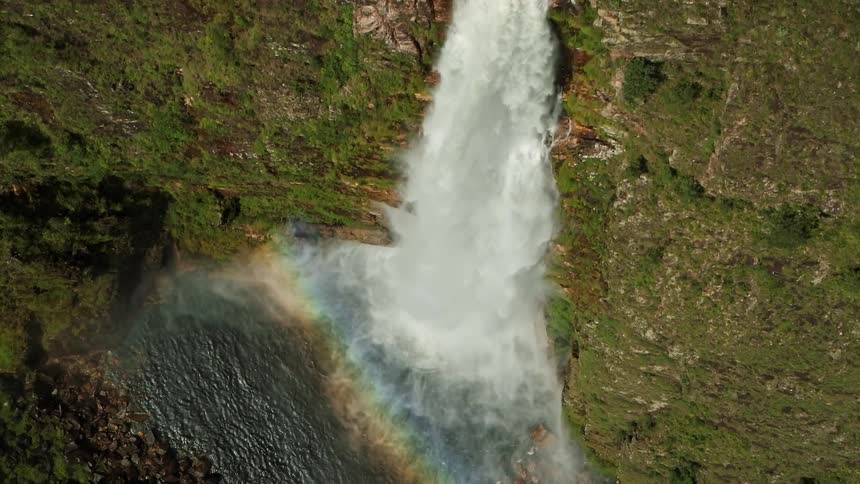 A waterfall splashes as it flows down the side of a moss covered mountain