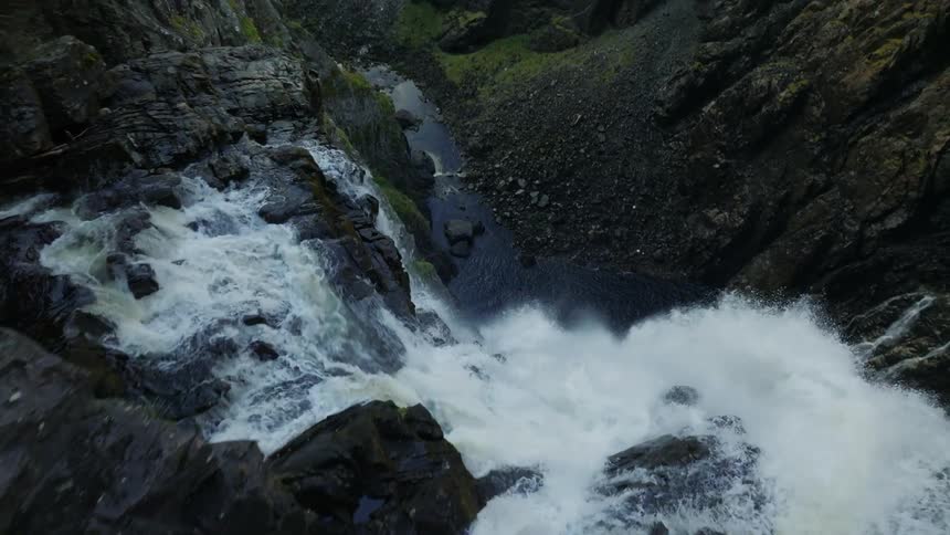 Aerial view of a powerful waterfall streaming down a canyon in the mountains