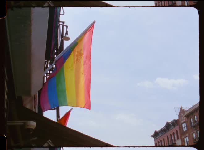 The rainbow colored flag hangs from the building