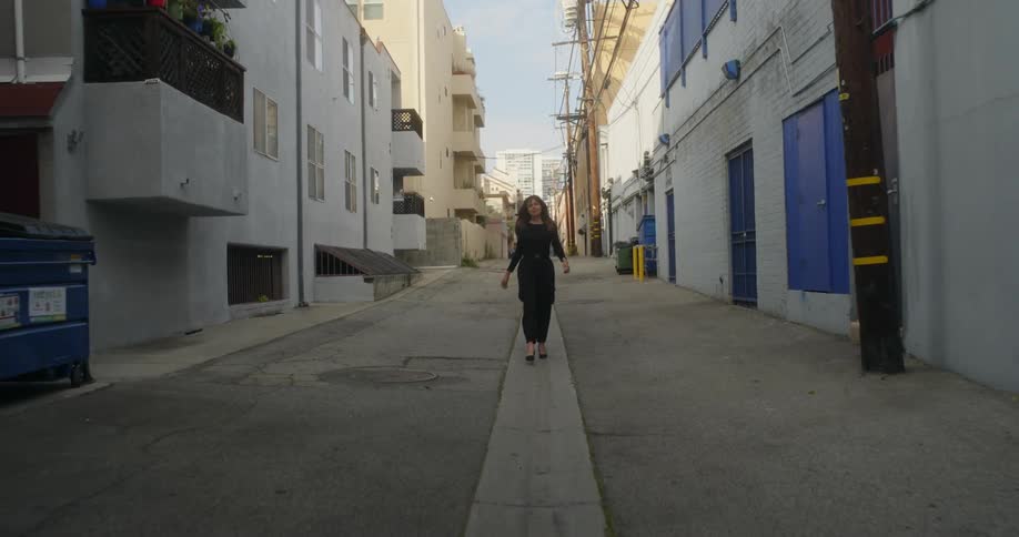 Young woman walking down an alley in the city at morning