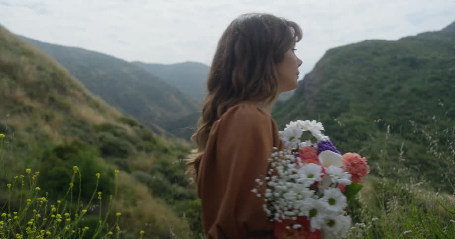 The view is of a woman that is walking outdoors as she is holding flowers