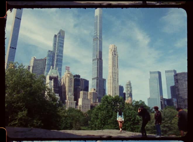 A view of a tower block from a city park with tourists taking photos