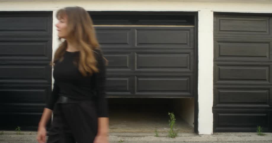 Female walking out of an empty storage unit smiling and then walking away