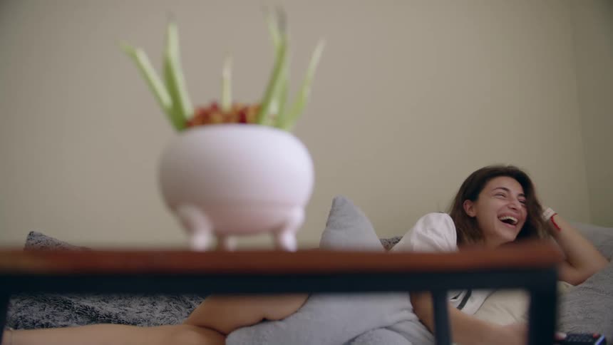 A woman talks and laughs while lying in a bed on her side relaxing