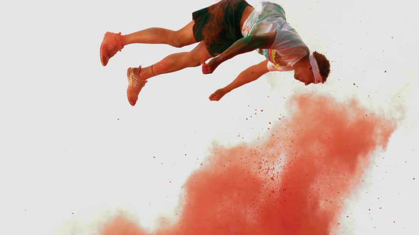 A young African American athlete does a flip with red powder