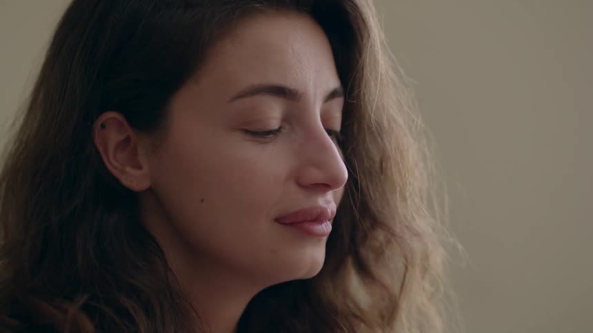 A woman takes a sip from her coffee cup and pauses to think