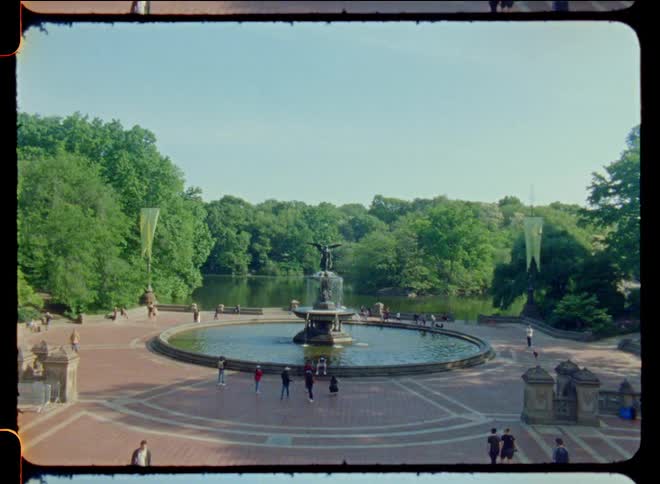 A fountain in central park with many people visiting it