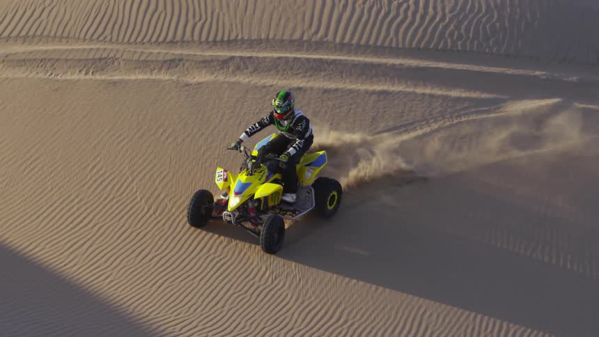 A person does a wheelie on his four wheeler in the desert