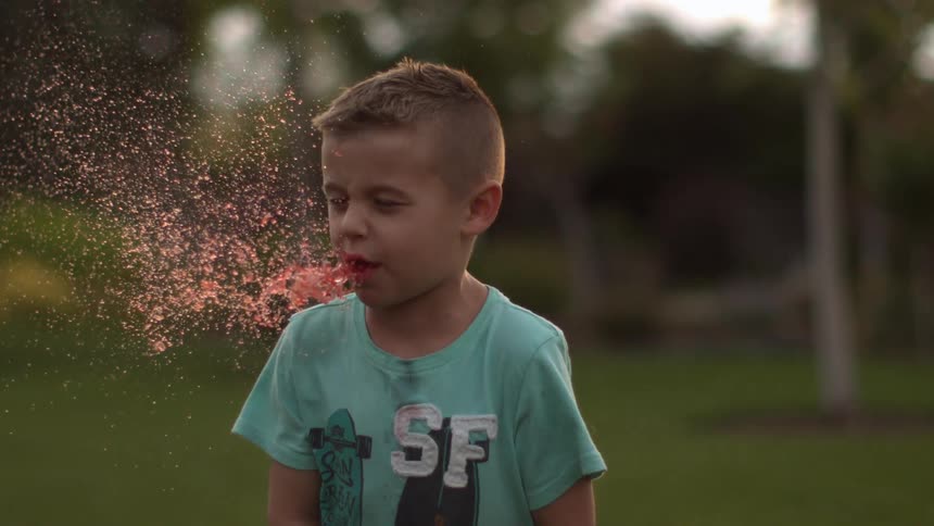 Slow motion shot of boy spitting out red liquid