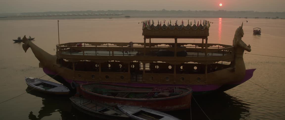 An ornate passenger boat with a sculpture of a woman in the front waiting at a dock