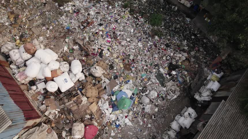 An aerial of garbage piled up in a third world country as people walk around on it