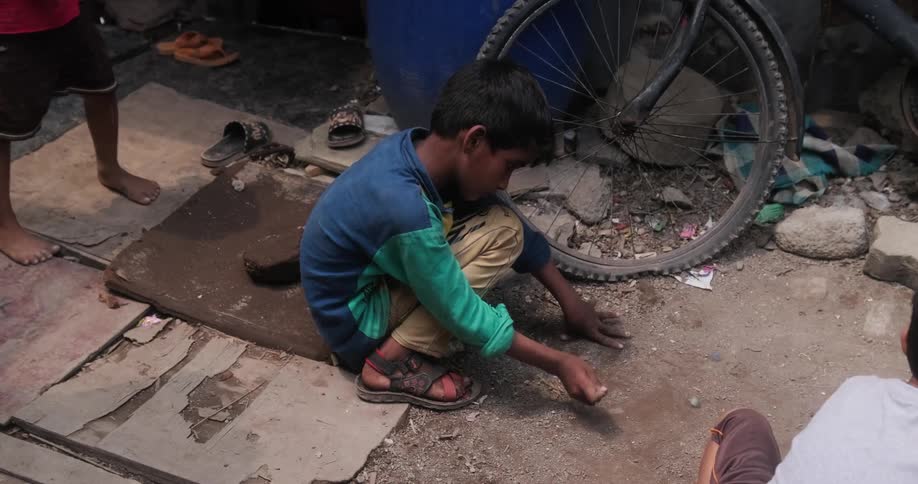 Young boys play with rocks in an alley