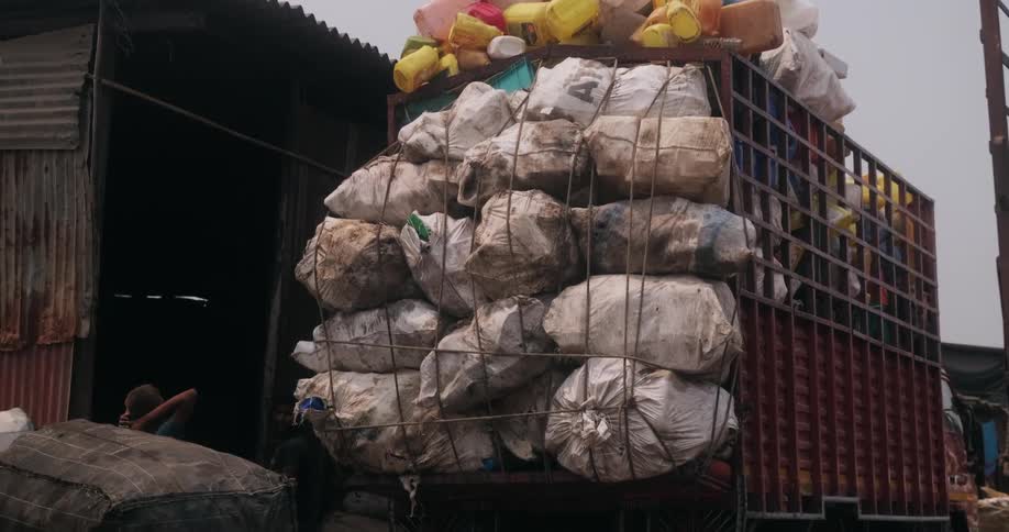 Garbage piled and overloading a dump truck parked out front of a shelter