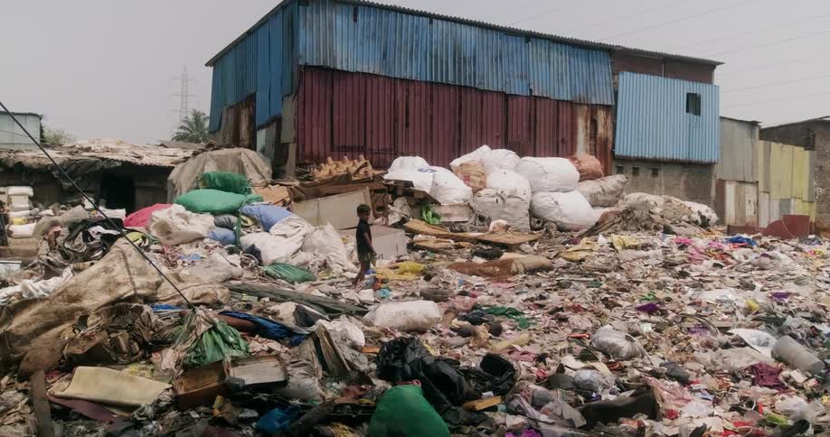 A young child walks through garbage in a slum