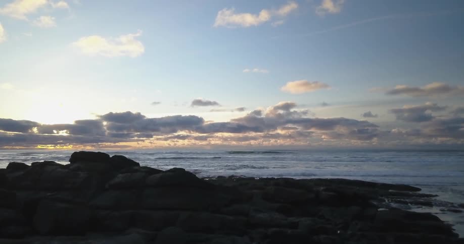 A person walks towards the rocks on the beach