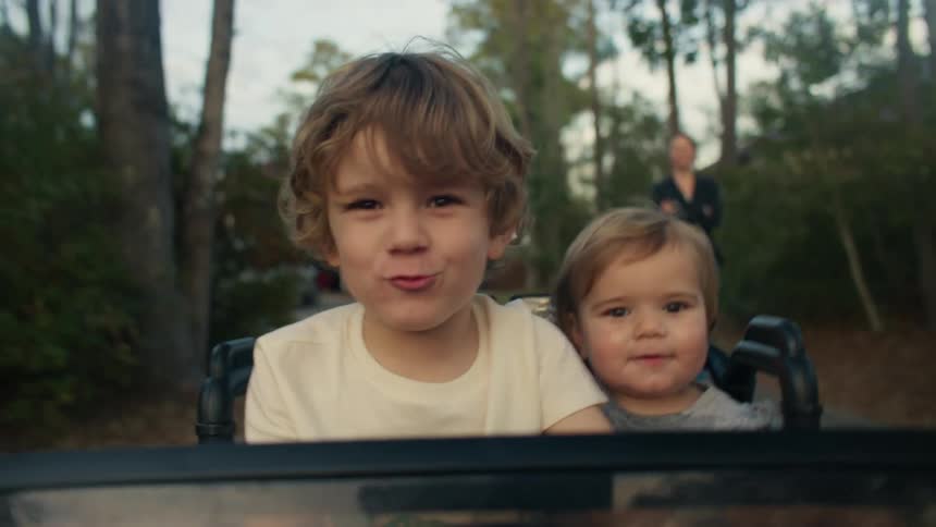 Kids are inside of a toy car around the nature area