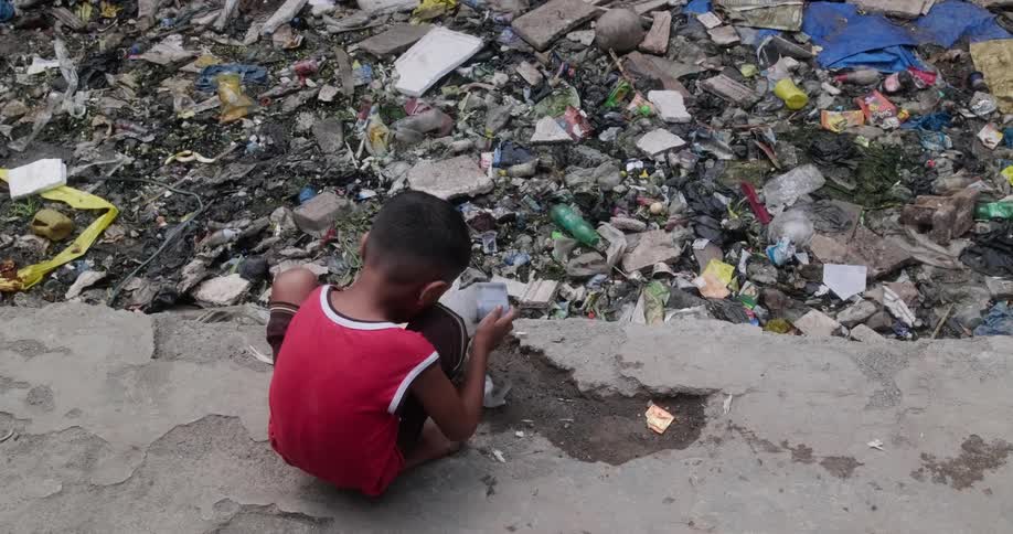 A young boy above a landfill playing with a toy made from trash