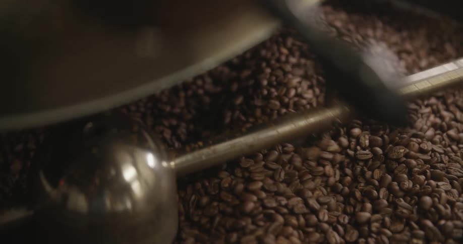 A machine turning and mixing coffee in a large container