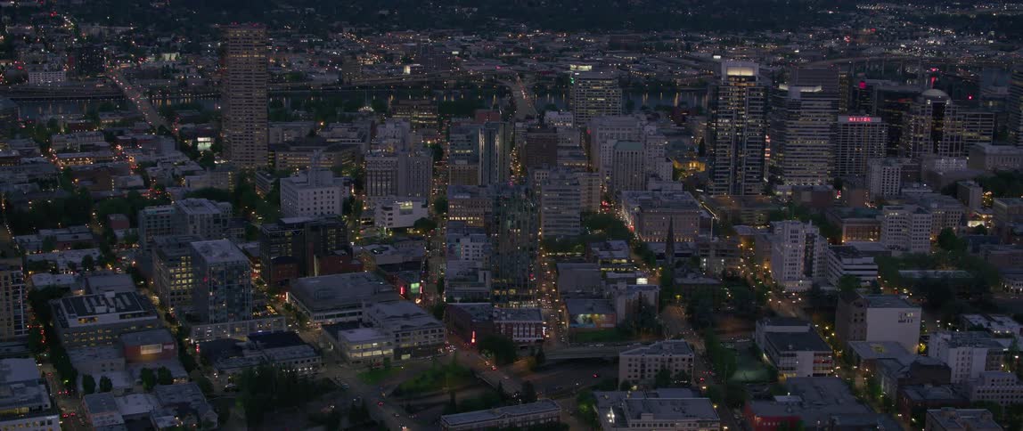 An aerial view of a city at night illuminated by the lights coming from the streets and buildings