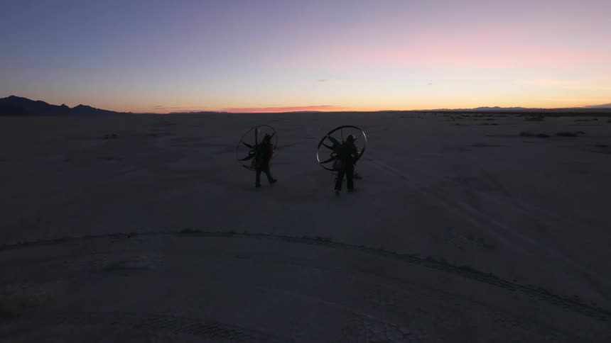 People walking while carrying large fans at sunset