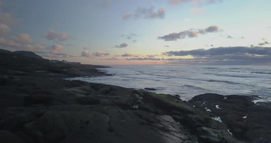 Man sitting on a boulder near the ocean after sunset