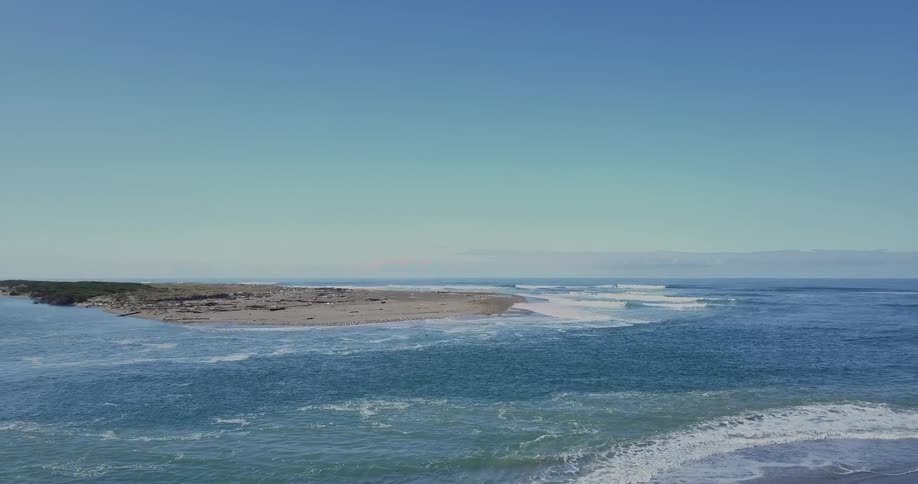 A beautiful ocean flows next to a beach covered in debris